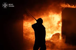 Рятувальник гасить пожежу після нічної атаки на Київ 26 липня